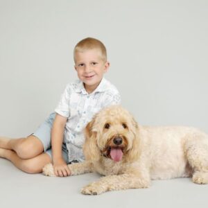Grey backdrop boy and his dog holding hands and paws for a studio shoot